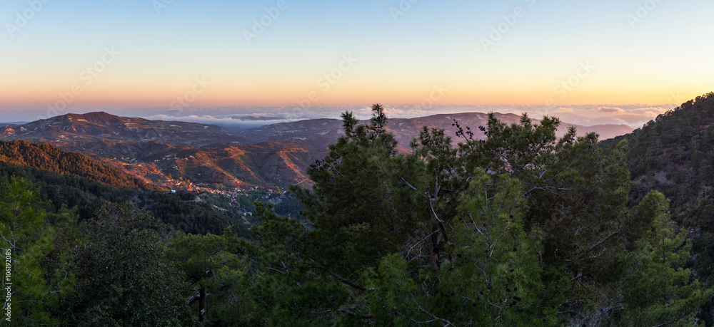 Panoramic view on mountain range with layer mist on evening glow background. Troodos, Cyprus.
