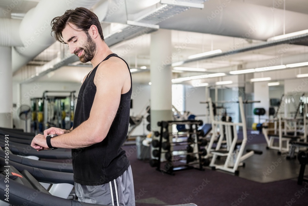 Smiling man on treadmill looking at smartwatch Smiling man on treadmill looking at smartwatch