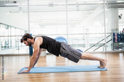 Muscular man doing push up on mat