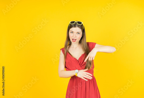 Youth and technology. Amazed young woman pointing  watch. Colorful studio portrait. Yellow background.