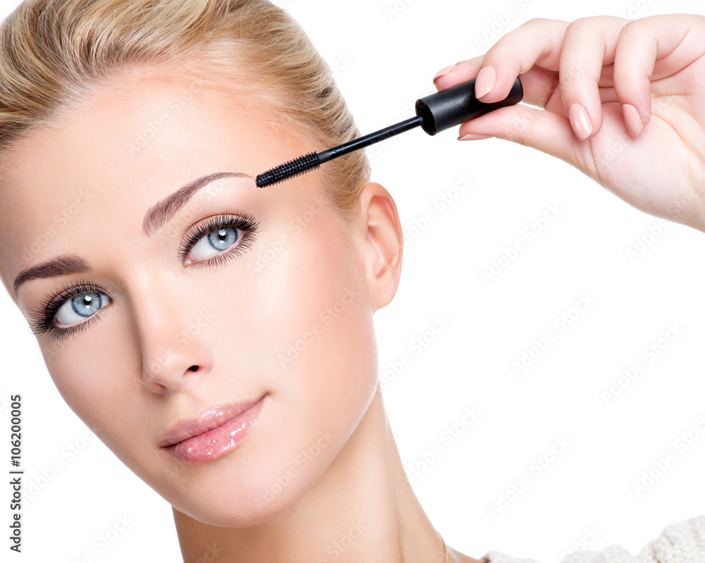 woman applying mascara on eyelashes