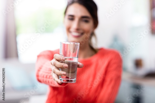 Billede på lærred Young woman showing drinking glass with water