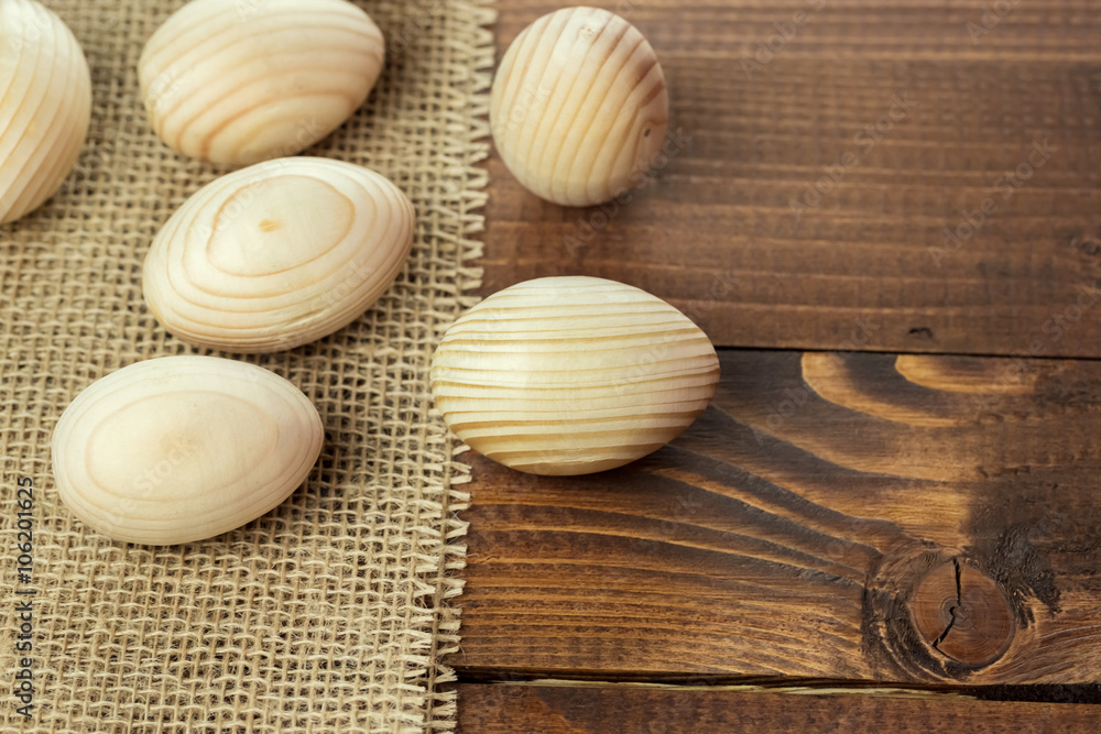 Beautiful wooden Easter eggs lying on the sacking and old brown boards, with free space for your text Beautiful wooden Easter eggs lying on the sacking and old brown boards, with free space for your text