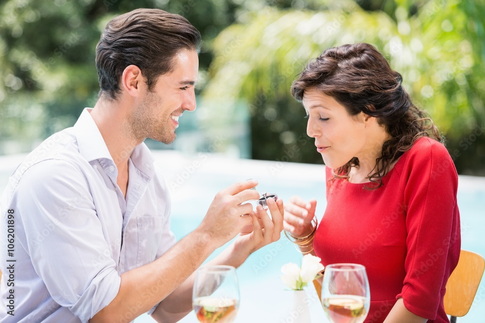 Young man giving engagement ring to surprised woman Young man giving engagement ring to surprised woman