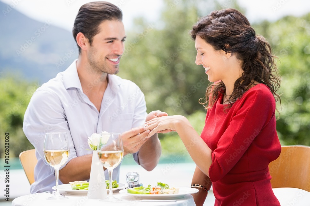 Smiling man wearing engagement ring to woman Smiling man wearing engagement ring to woman