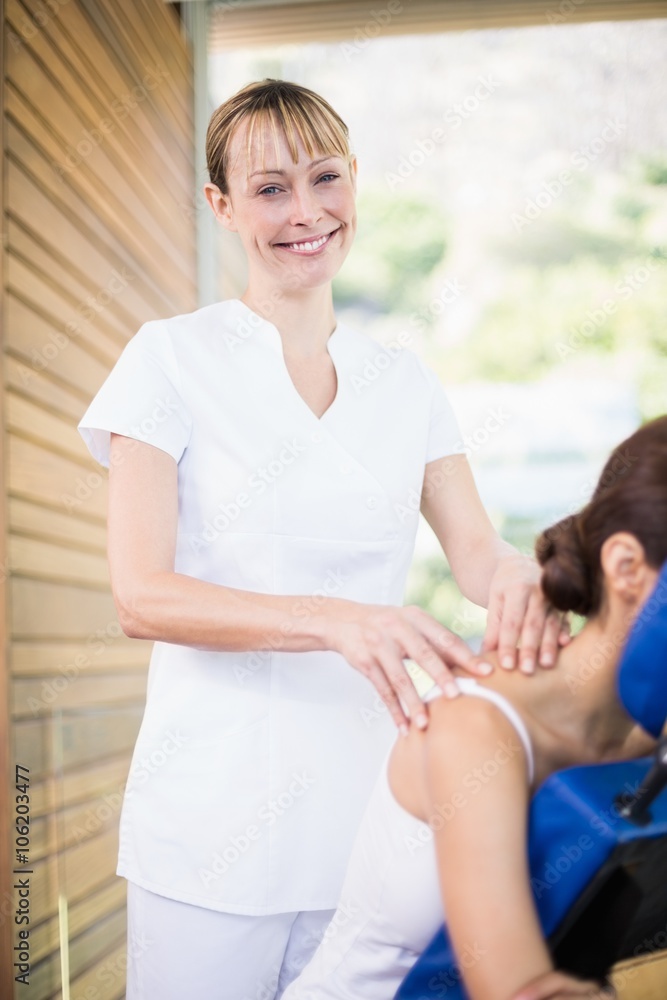 Fototapeta premium Portrait of happy physiotherapist giving shoulder massage