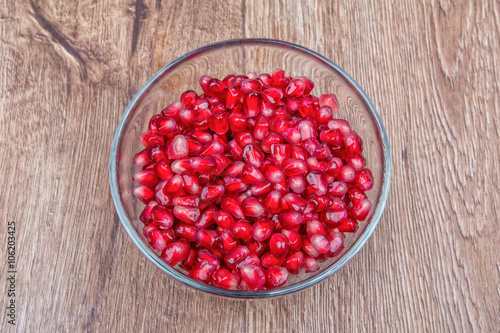 Fresh organic pomegranate seeds in a bowl on a background