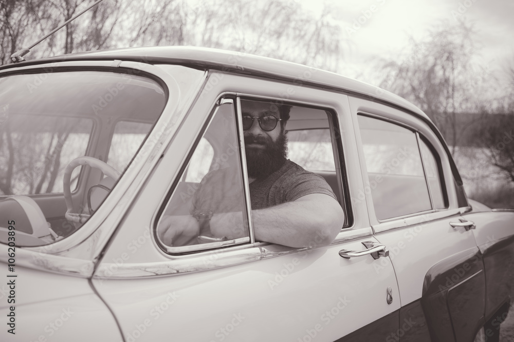 Obraz premium Bearded man behind the wheel of a retro car