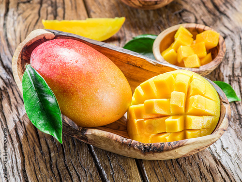 Obraz na płótnie Mango fruit and mango cubes on the wooden table.