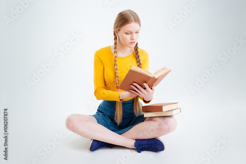 Female student sitting on the floor and reading book