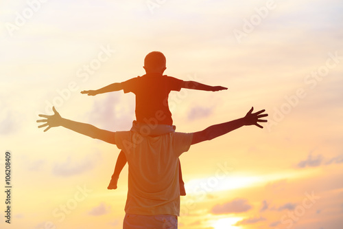 father and son play on sunset sky