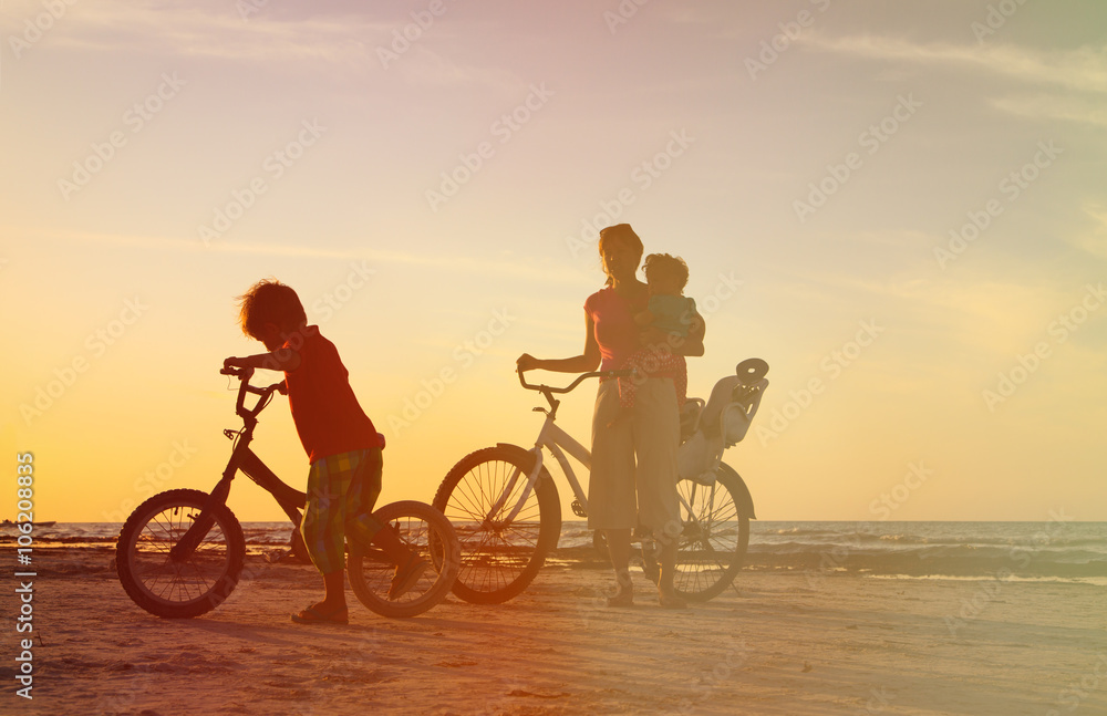 Fototapeta premium happy mother with two kids biking at sunset