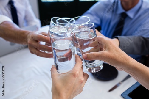 Slika na platnu Group of businesspeople toasting glass of water in restaurant