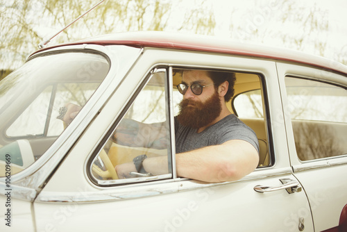 Bearded man behind the wheel of a retro car