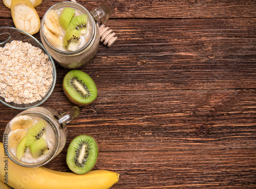 Smoothies with oatmeal, banana, kiwi in glass jars on a wooden background.Concept of cooking.  