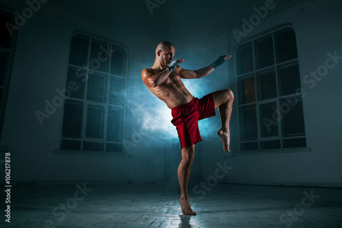 The young man kickboxing in blue smoke