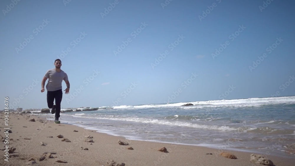 Young male running on sand in slow motion Young male running on sand in slow motion