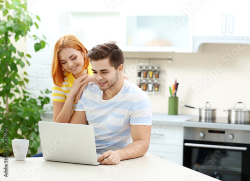 Happy young couple using la...