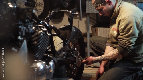 Auto mechanic assembles custom motorcycle in his workshop. Create an exclusive moto bike in the garage.