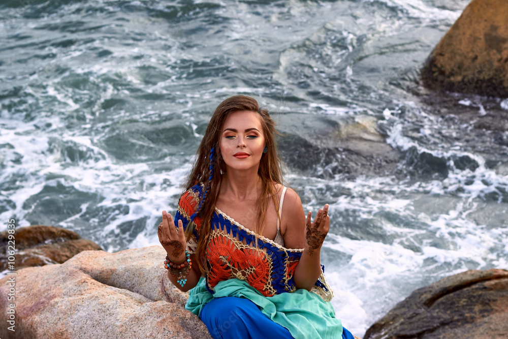 Beautiful girl, bright clothes  yoga posing, summer stone beach, sea