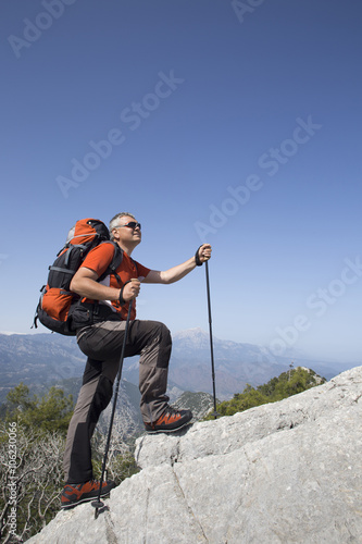 A traveler stands on top of a mountain and looks out to sea.