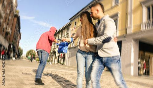 Bag snatching scene outdoors - Couple robbed by pickpockets - Purse snatcher action downtown street - Daily crime event by hooded guy - Focus on the bag shallow depth of field and radial zoom defocus
