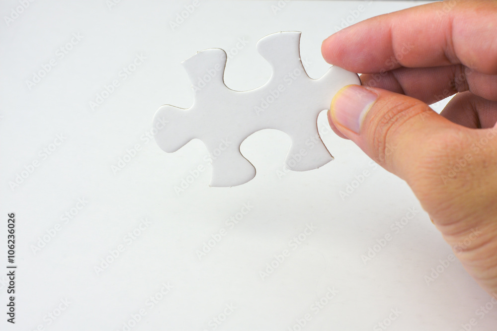 Hand holding a piece of puzzle Hand holding a piece of puzzle