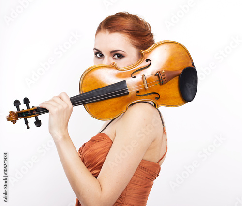 Young red-haired girl with a violin in her hands on a white background.evening dress.Long orange dress 