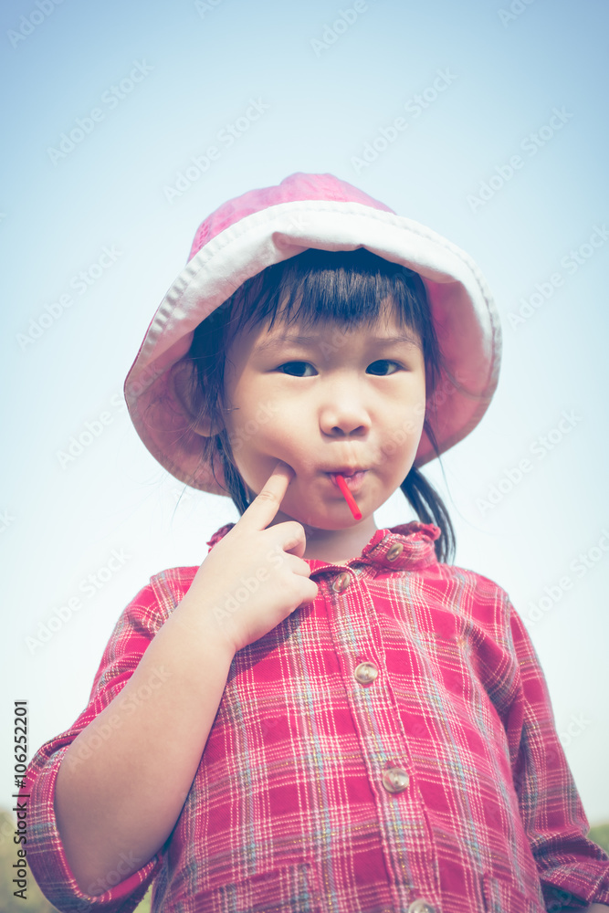Cute little asian girl eating a lollipop on nature background Cute little asian girl eating a lollipop on nature background