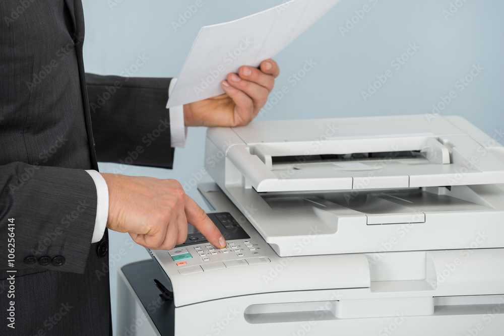 Close-up Of Businessman Pressing Printer's Button In Office Close-up Of Businessman Pressing Printer's Button In Office
