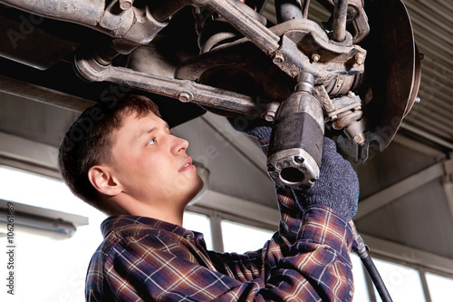 Car mechanic inspecting car wheel and suspension detail of lifte photo