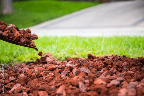 shovel placing red lava rock