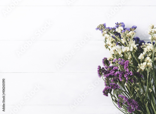 Bouquet of dried wild flowers on white table background with natural wood vintage planks wooden texture top view horizontal  empty space for publicity information or advertising text