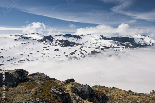 Mountain peaks above the clouds with blue sky and white clouds, view from the mountain Dalsnibba, Norway