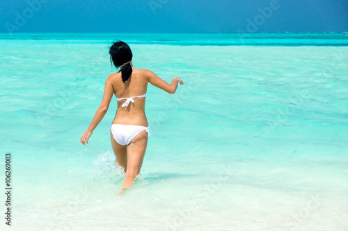 Красивая девушка в белом купальнике в прозрачной голубой воде тропического океана