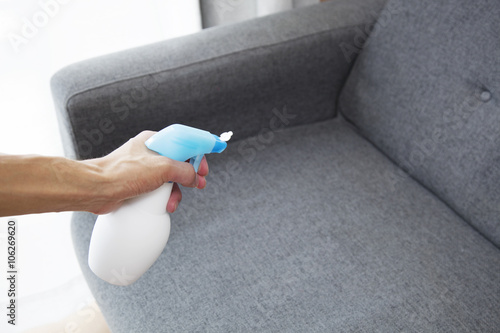 Sprayed air freshener in hand on home interior background
