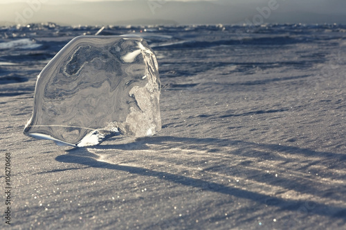 Transparent piece of ice and shadows on the snow. photo