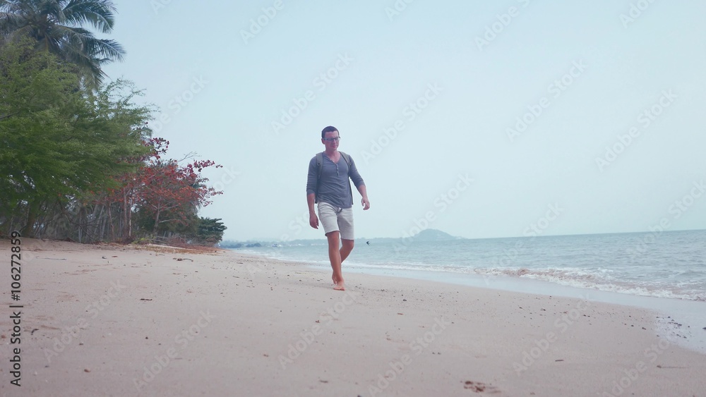 Man walk on the background of beautiful beach with white sand and cloudy sky Man walk on the background of beautiful beach with white sand and cloudy sky