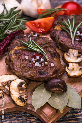Beef steak with herbs and rosemary, fresh juicy on a wooden table background. Seleсtive focus