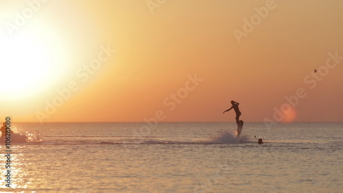 Silhouette of a Man Having Fun on Flyboard in the Sea at Sunset Background