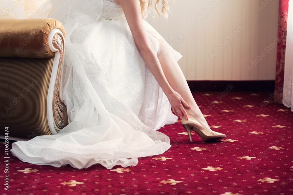 Fototapeta premium the bride puts on elegant wedding shoes.