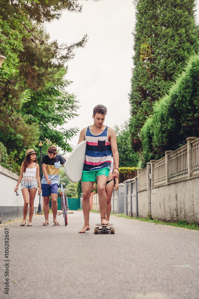 Obraz premium Young man riding on skate and holding surfboard
