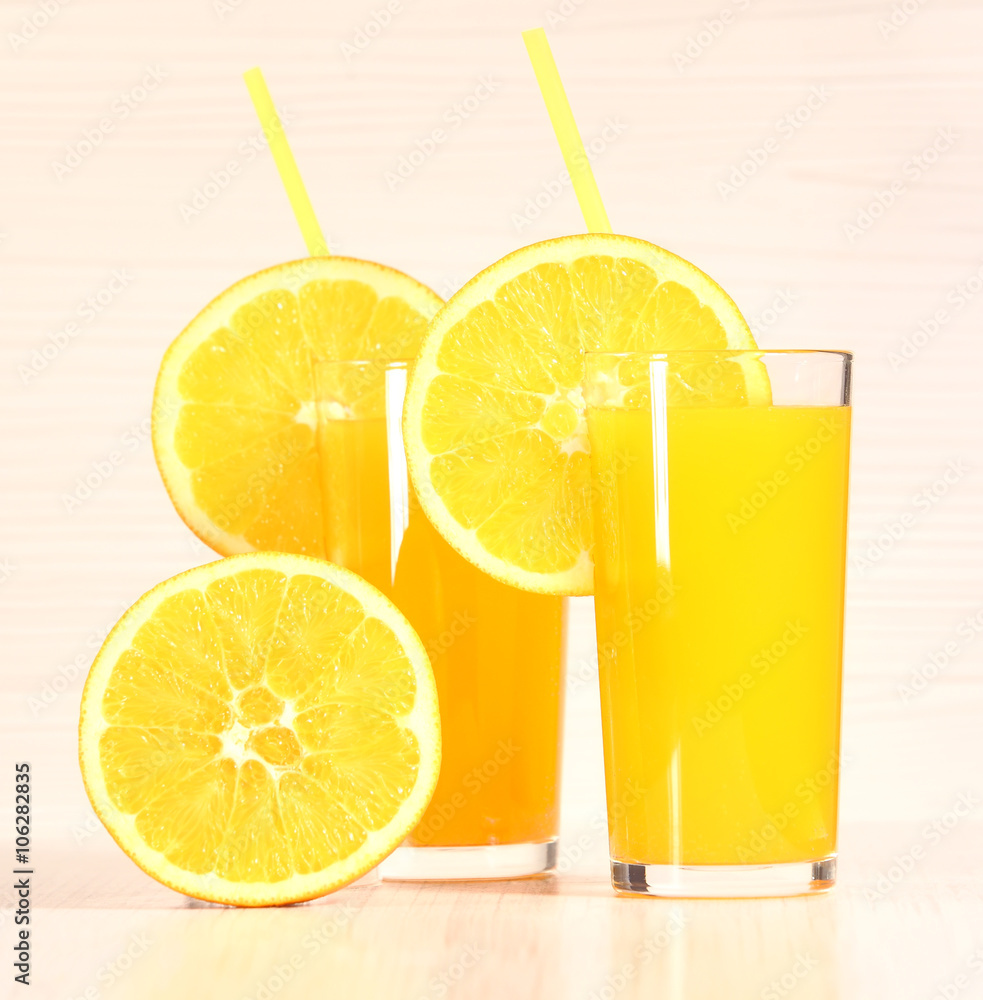 Fresh orange lemonade or juice in a glass next to the whole fruit and orange slices on a light gray background Fresh orange lemonade or juice in a glass next to the whole fruit and orange slices on a light gray background