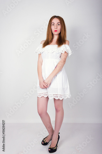 Beautiful slim girl in a small white lace dress posing