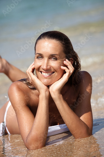 portrait de femme caucasienne souriant à la mer couchée dans le sable