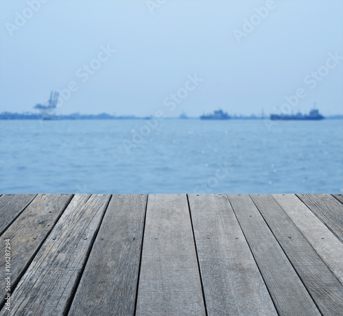 Empty old wood floor over blur of cargo ship with shipping port,