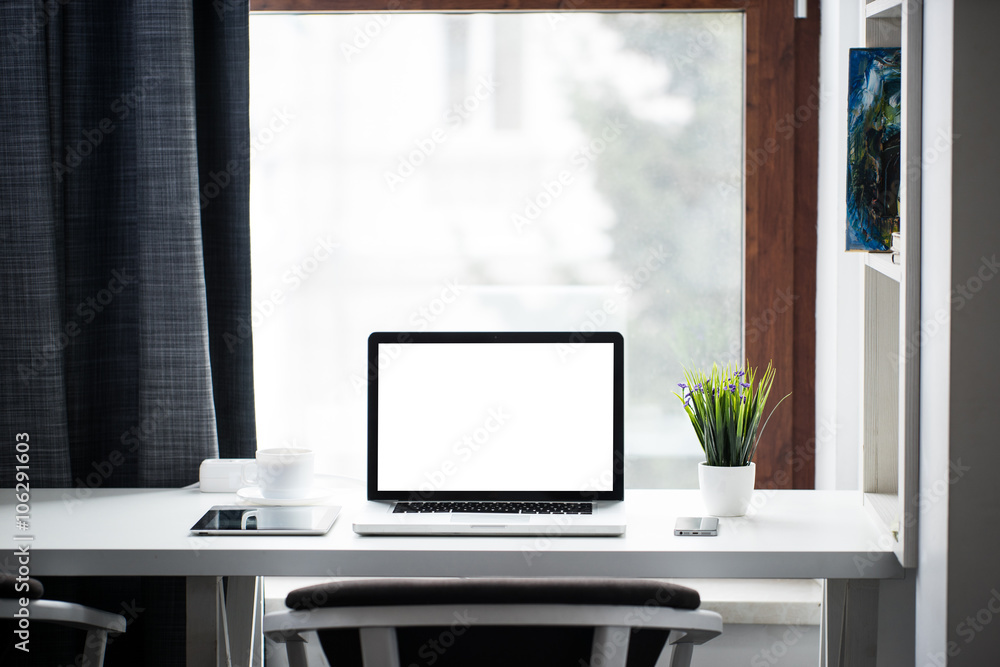 Fototapeta premium Office desk next to a window with laptop and tablet pc and a sma