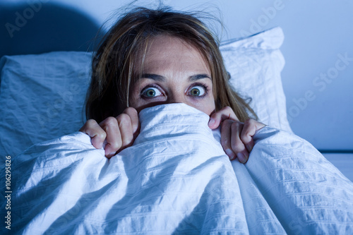 femme au lit cachée sous les draps apeurée © plprod