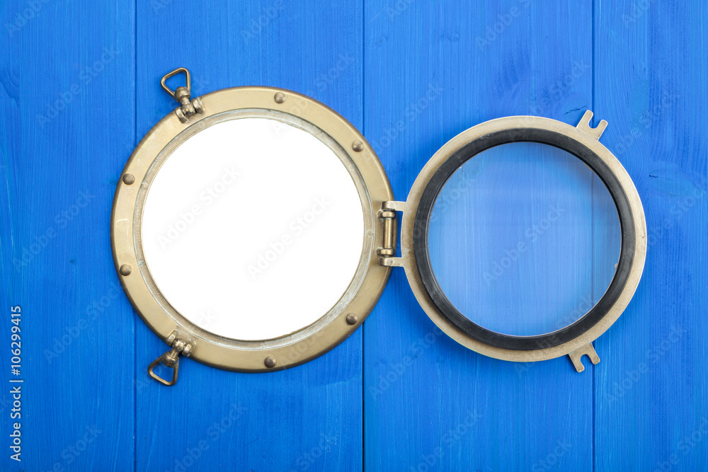 Brass porthole in blue wooden wall, opened, with clipping path Stock