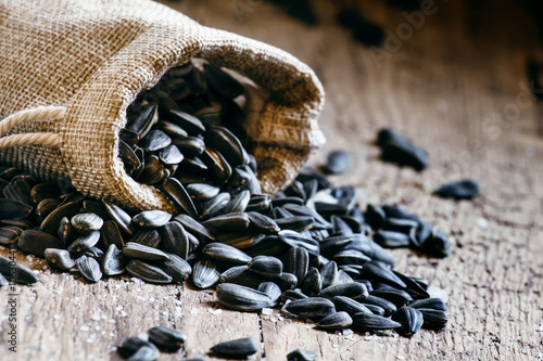 Sunflower seeds in a canvas bag, old wooden background, selectiv photo